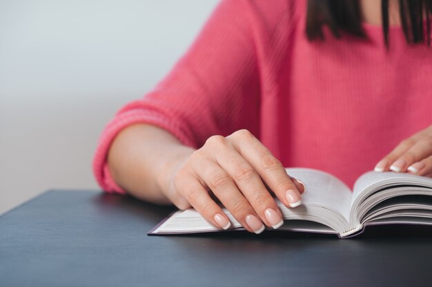 Mujer joven está leyendo un libro en casa.