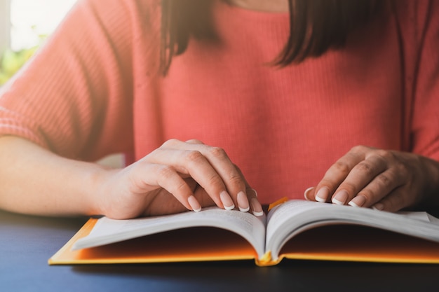 Mujer joven está leyendo un libro en casa.