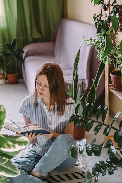 Una mujer joven está leyendo un libro mientras está en cuarentena en casa.