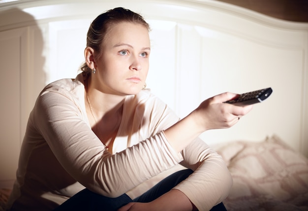 La mujer joven está mirando la televisión