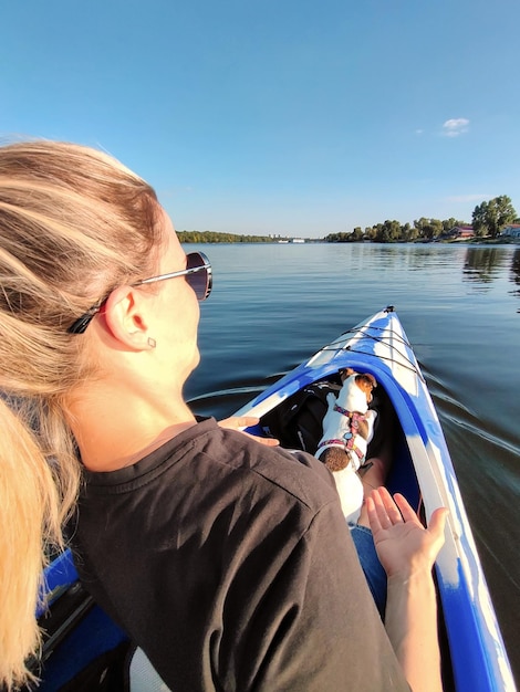 Una mujer joven está navegando en un barco con un perro Jack Russell en el hombro Recreación activa