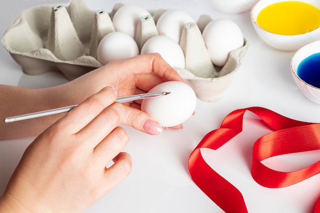 Una mujer joven está pintando sobre huevos de Pascua