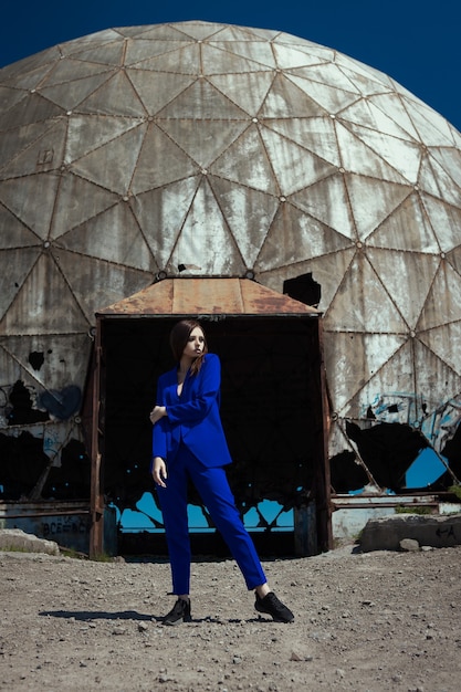 Mujer joven está posando en un traje casual azul frente al viejo radar dopler