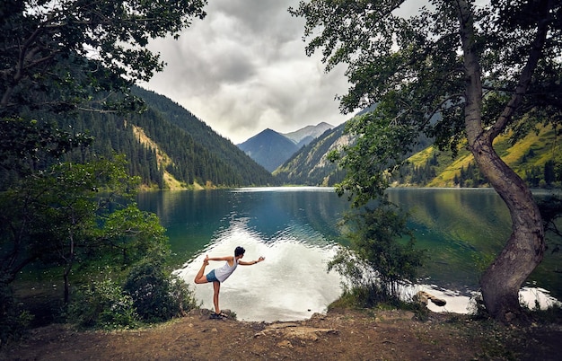 La mujer joven está practicando yoga al aire libre