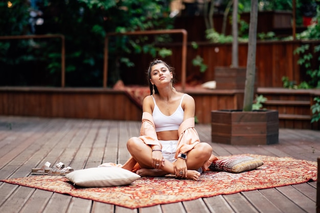 La mujer joven está practicando yoga sentada en un podio de madera