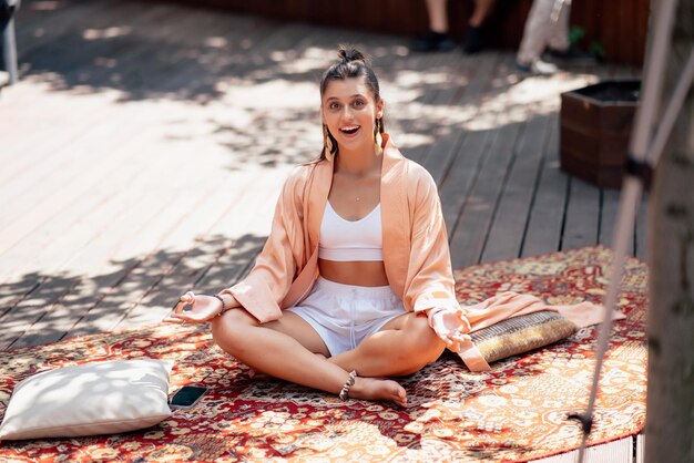 La mujer joven está practicando yoga sentada en un podio de madera