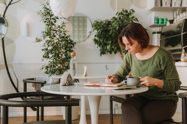 Una mujer joven está sentada en una mesa en un café.