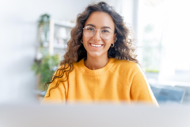 La mujer joven está usando una computadora portátil. Chica divertida divirtiéndose quedándose en casa.