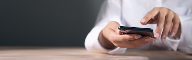 Una mujer joven está usando su teléfono inteligente en una mesa