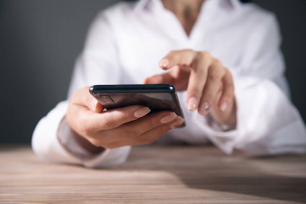 Una mujer joven está usando su teléfono inteligente en una mesa