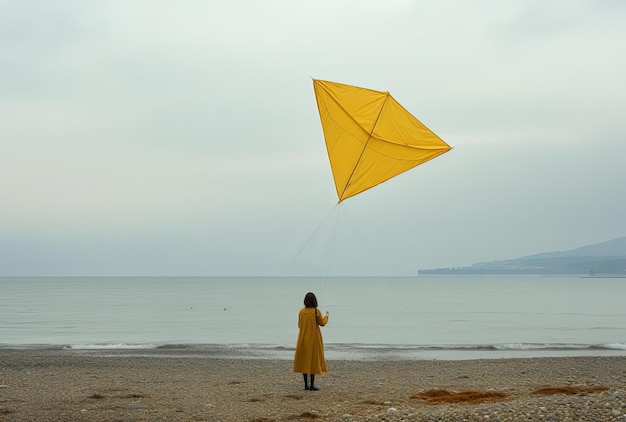 una mujer joven está volando una cometa en la playa en un impermeable en el estilo de amarillo y gris