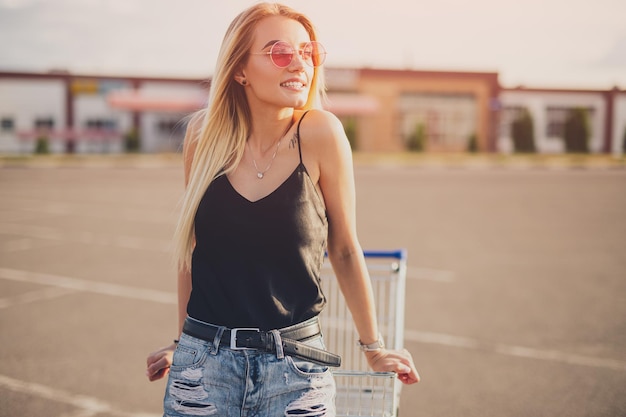 Mujer joven con estilo con carrito de compras