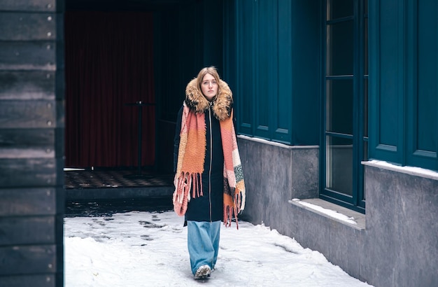 Mujer joven con estilo en una chaqueta y con una bufanda en un paseo en invierno