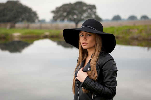 Mujer joven con estilo con hermoso sombrero en el campo