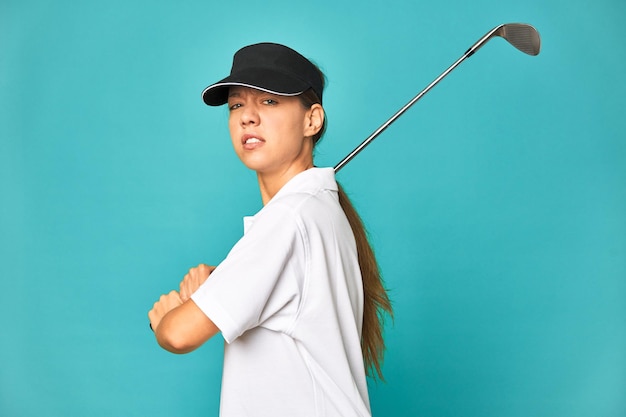 Mujer joven con estilo jugando al golf en el estudio