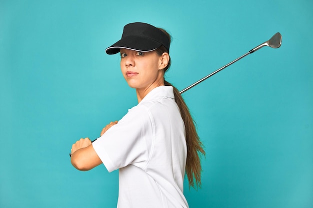 Mujer joven con estilo jugando al golf en el estudio