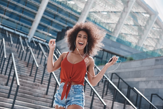 Mujer joven en estilo libre de auriculares en la calle saltando sobre sta