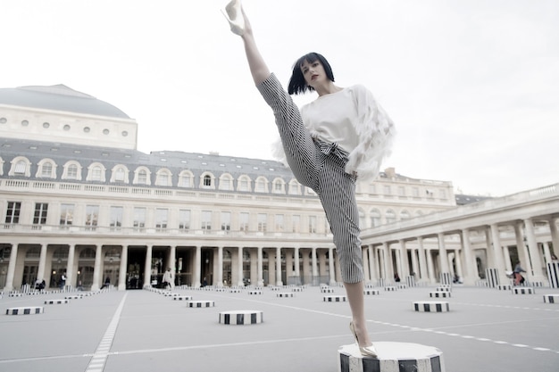 Mujer joven con estilo en pantalones con split en la calle en París, Francia. concepto de dace y yoga. pose de baile