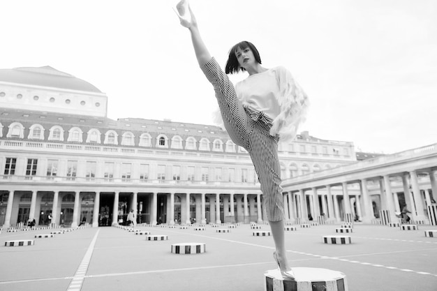 Mujer joven con estilo en pantalones con split en la calle en París Francia dace y concepto de yoga pose de baile