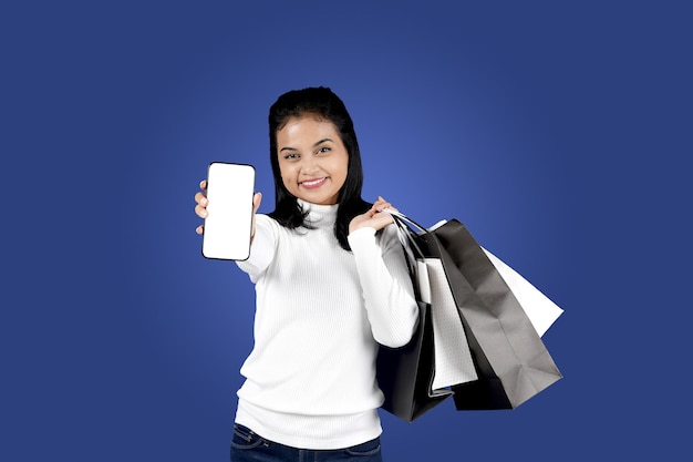 Mujer joven con estilo posando alegremente con bolsas de compras