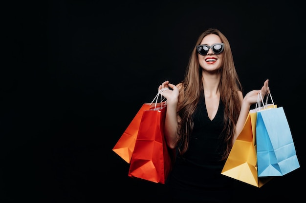 Mujer joven con estilo posando con bolsas de compras de moda