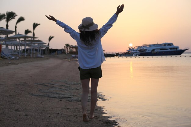 Mujer joven con estilo posando cerca del lago en el atardecer del día de verano