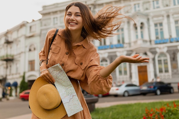 Mujer joven con estilo que viaja por Europa vestida con un bolso de sombrero de moda de primavera y accesorios sonriendo feliz divirtiéndose