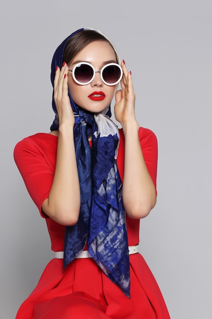 Mujer joven en estilo retro con gafas de sol y pañuelo de seda. Mujer retro de moda estilo años sesenta.