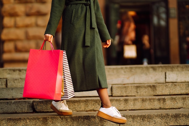 Mujer joven con estilo en ropa de moda con bolsas de la compra después de ir de compras el viernes negro
