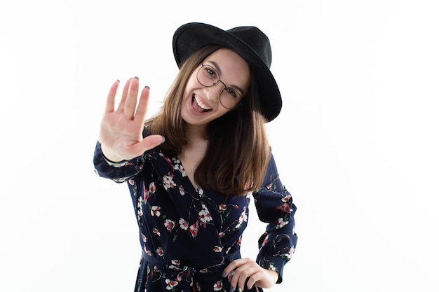 Una mujer joven con estilo en un sombrero y un vestido posa en el estudio sobre un fondo blanco Industria de la moda modelo sonriente