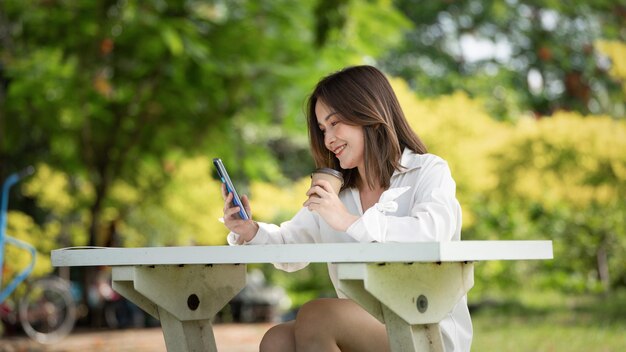 Mujer joven con estilo tomando café y usando un vaso de papel e ir a un parque jóvenes mujeres