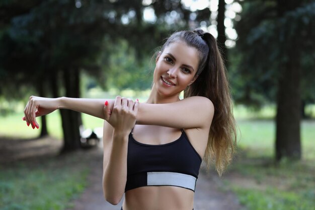 Mujer joven estirando los brazos antes del entrenamiento matutino al aire libre