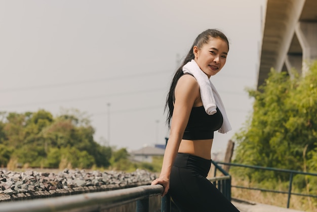 Mujer joven estirando el cuerpo después de trotar, feliz mujer milenaria deportiva corriendo en el muelle