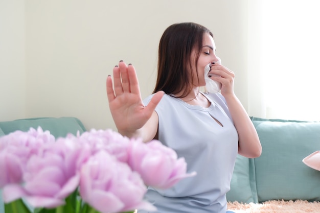 Mujer joven estornuda por alergia a las flores. Alergia al polen