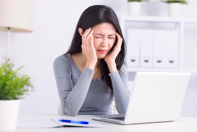 Mujer joven estresada que sufre de dolor de cabeza después del trabajo en la computadora