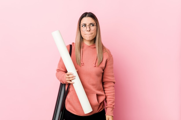 Mujer joven estudiando arquitectura confundida, se siente dudosa e insegura.