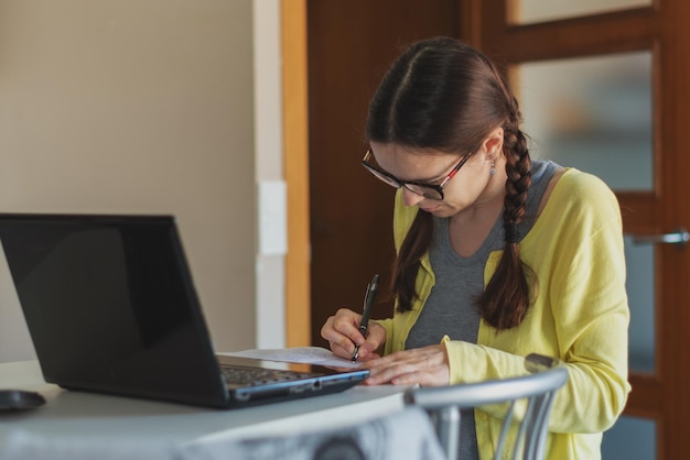 Mujer joven estudiando en casa con una computadora portátil