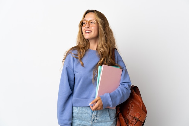 Mujer joven estudiante aislada mirando hacia el lado y sonriendo