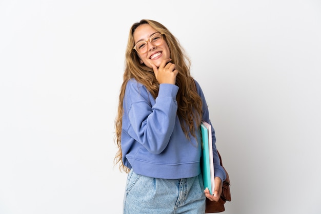 Mujer joven estudiante aislada en la pared blanca feliz y sonriente