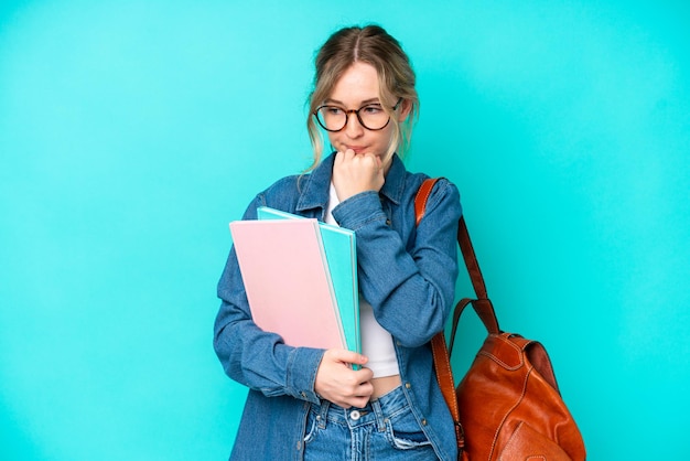 Mujer joven estudiante aislada sobre fondo azul que tiene dudas