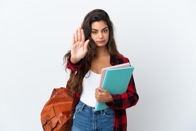 Mujer joven estudiante aislada sobre fondo blanco haciendo gesto de parada