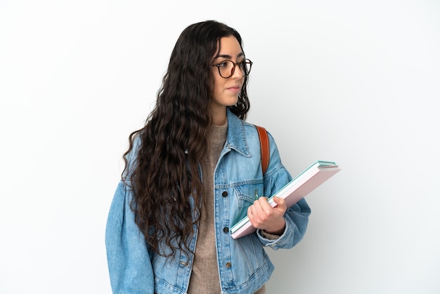 Mujer joven estudiante aislada sobre fondo blanco mirando hacia el lado