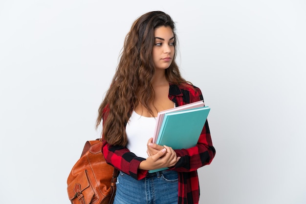 Mujer joven estudiante aislada sobre fondo blanco mirando hacia el lado