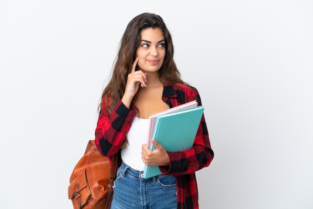 Mujer joven estudiante aislada sobre fondo blanco pensando en una idea mientras mira hacia arriba