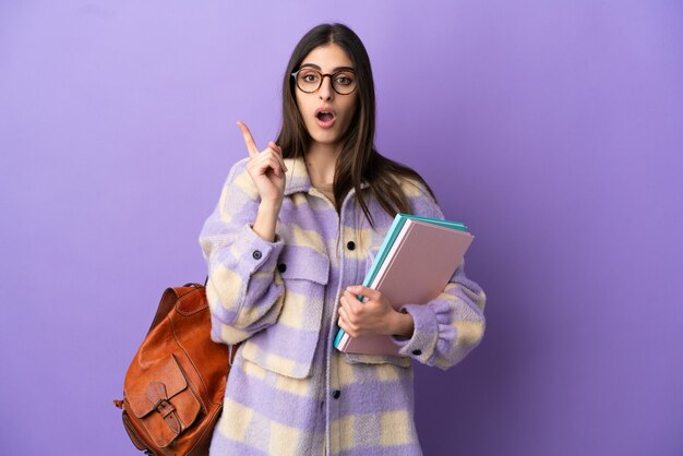 Foto mujer joven estudiante aislada sobre fondo púrpura con la intención de darse cuenta de la solución mientras levanta un dedo