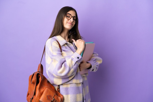 Mujer joven estudiante aislada sobre fondo púrpura orgulloso y satisfecho de sí mismo