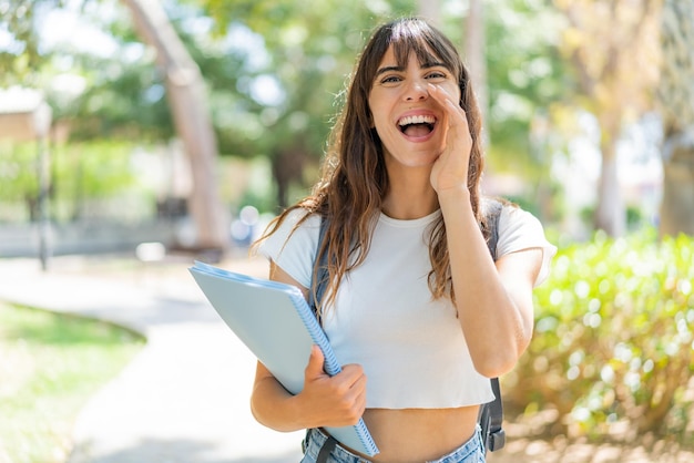 Mujer joven estudiante al aire libre gritando con la boca abierta