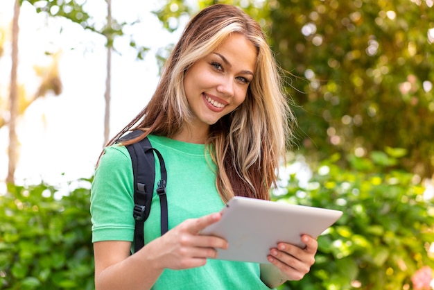 Mujer joven estudiante al aire libre sosteniendo una tableta