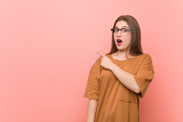 Mujer joven estudiante con anteojos apuntando hacia el lado