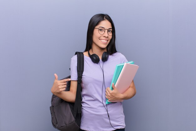 Mujer joven estudiante bastante latino contra la pared gris